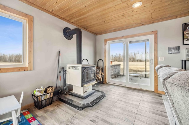 interior space featuring wooden ceiling, a wood stove, wood finished floors, and baseboards