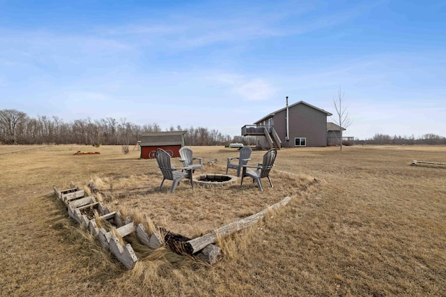 view of yard with an outbuilding, a rural view, an outdoor fire pit, and a storage shed