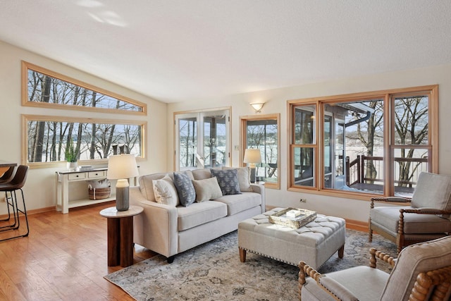 living area featuring vaulted ceiling, baseboards, and wood-type flooring