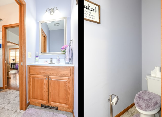 half bathroom with vanity, visible vents, baseboards, tile patterned flooring, and toilet