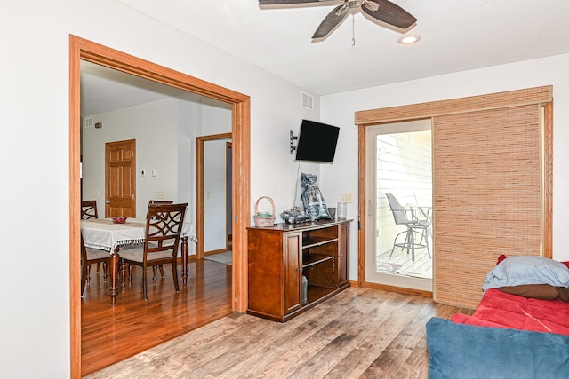 living area with visible vents, baseboards, light wood-type flooring, and a ceiling fan