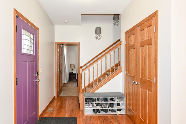 foyer with visible vents, stairs, baseboards, and wood finished floors