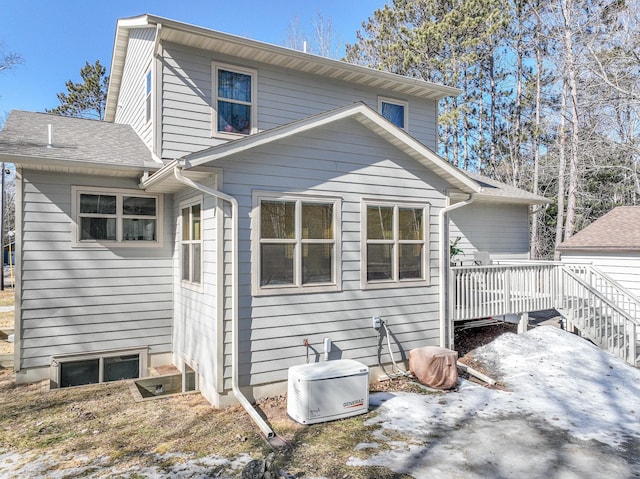 back of house with roof with shingles and a wooden deck