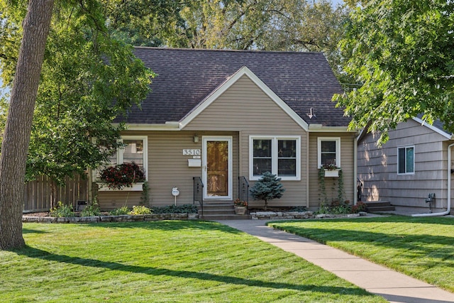 cape cod house with entry steps, a front lawn, fence, and roof with shingles