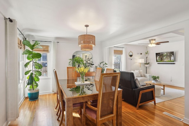 dining space with visible vents, baseboards, light wood-style flooring, and a ceiling fan