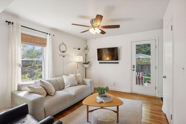 living room with baseboards, wood finished floors, and a ceiling fan