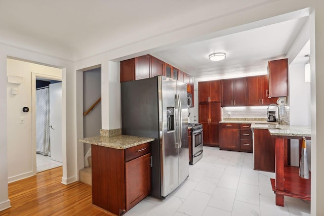 kitchen featuring backsplash, dark brown cabinets, stainless steel appliances, and a sink