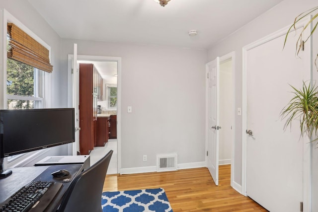 office space with light wood-style flooring, baseboards, and visible vents