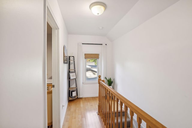 hallway featuring lofted ceiling, an upstairs landing, and light wood-type flooring