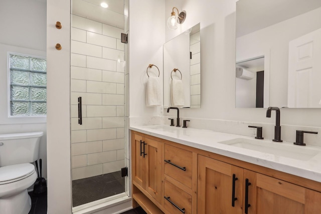 full bathroom with double vanity, toilet, a stall shower, and a sink