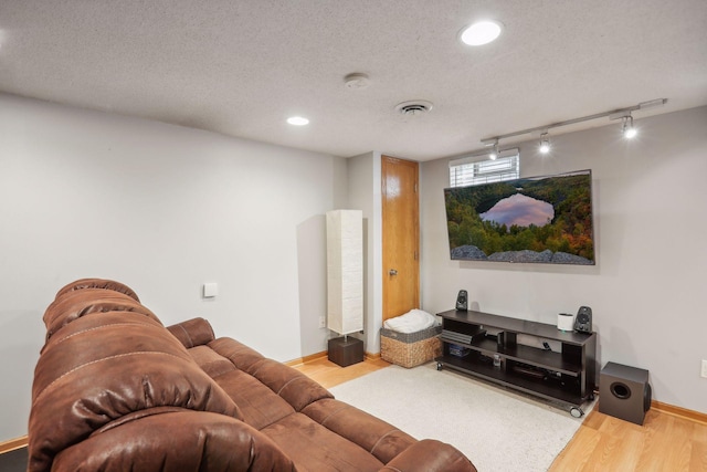 home theater featuring wood finished floors, visible vents, and a textured ceiling