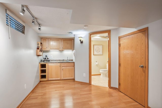 bar with a sink, baseboards, a textured ceiling, and light wood-style flooring