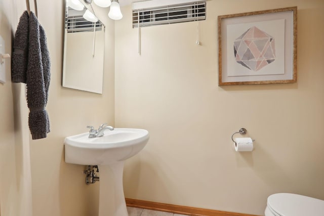 half bathroom with baseboards and toilet