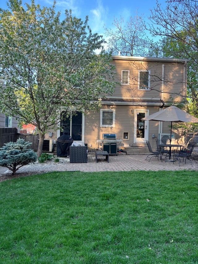 rear view of house featuring a patio, fence, and a lawn