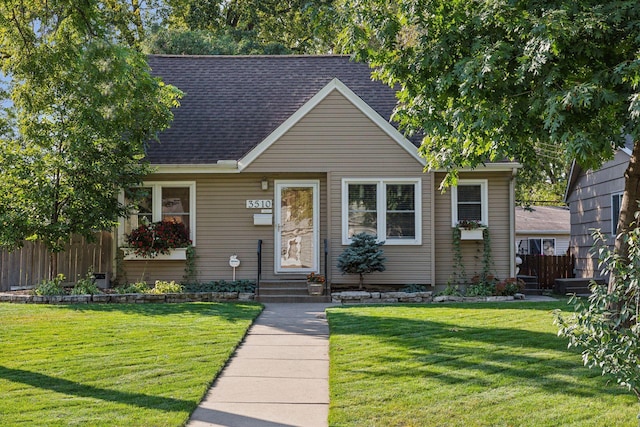 view of front of property with fence, a shingled roof, a front lawn, and entry steps