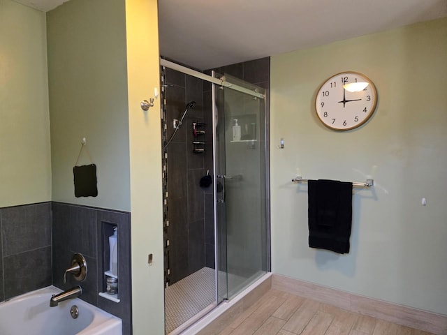 full bathroom featuring wood finished floors, a garden tub, and a stall shower