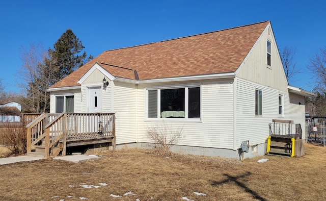 view of front of house with roof with shingles, a deck, and fence