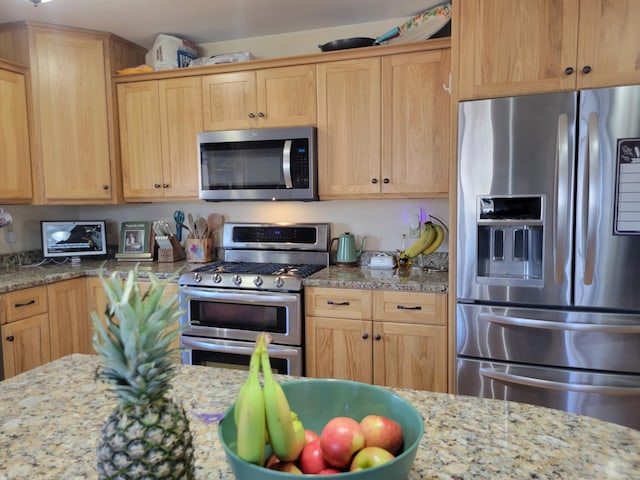 kitchen with light stone counters, appliances with stainless steel finishes, and light brown cabinets