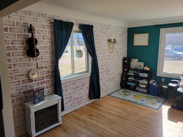 interior space with plenty of natural light, wood finished floors, and brick wall