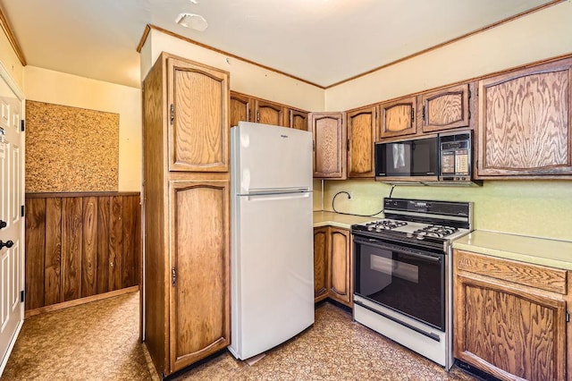 900 Park St, Anoka, MN 55303 - kitchen with gas stove, black microwave, freestanding refrigerator, light countertops, and a wainscoted wall