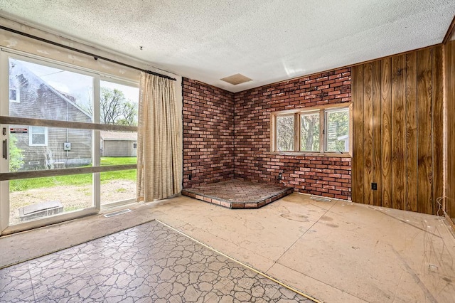 900 Park St, Anoka, MN 55303 - empty room with healthy amount of natural light, a textured ceiling, and brick wall