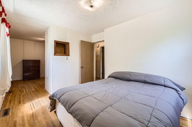 900 Park St, Anoka, MN 55303 - bedroom featuring wallpapered walls, light wood-style flooring, and a textured ceiling
