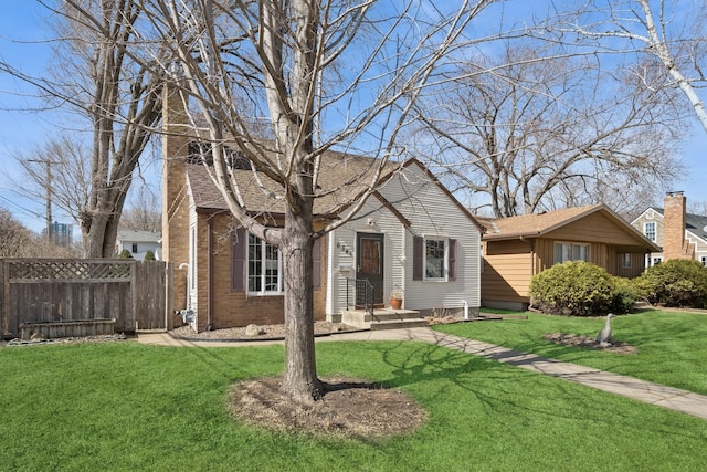 view of front of property featuring brick siding, a front yard, and fence