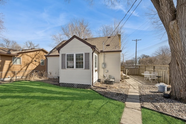 back of house with a yard, a patio, roof with shingles, and fence