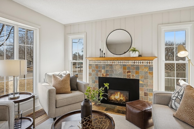 living room with visible vents, baseboards, wood finished floors, a glass covered fireplace, and a textured ceiling