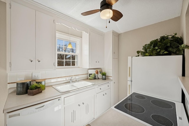 kitchen featuring white appliances, a sink, light countertops, white cabinets, and tasteful backsplash