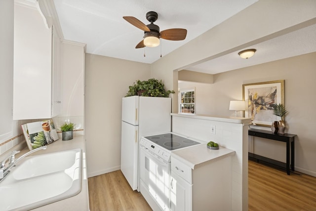 kitchen with white appliances, light countertops, light wood-style floors, and a sink