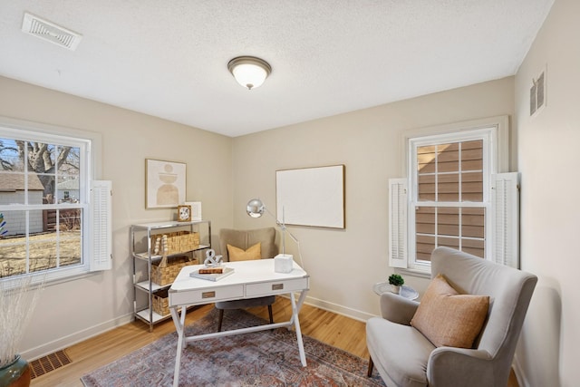 office area featuring visible vents, baseboards, and wood finished floors