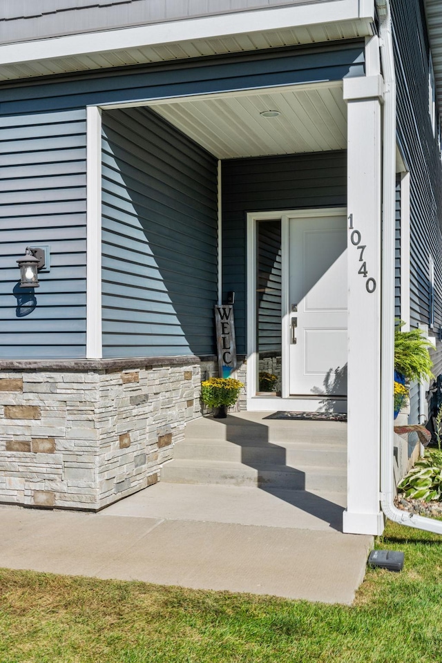 doorway to property with stone siding and covered porch