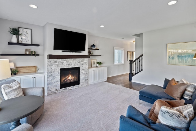 living area featuring carpet, baseboards, recessed lighting, stairs, and a stone fireplace