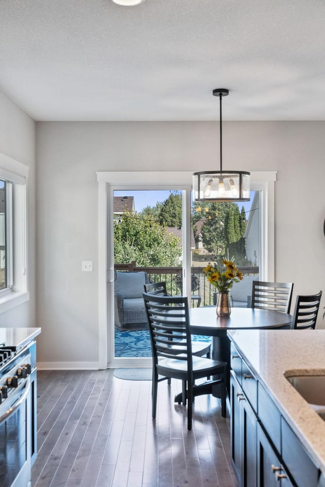 kitchen featuring hanging light fixtures, light stone countertops, dark wood-style flooring, and stainless steel range with gas stovetop