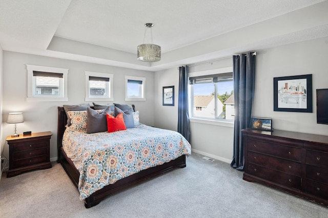 bedroom with a tray ceiling, baseboards, carpet, and visible vents