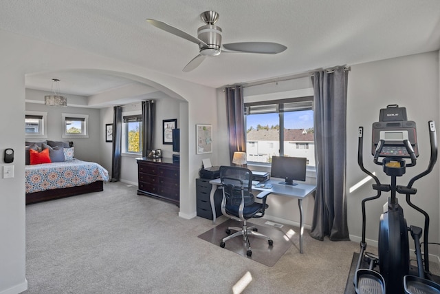 carpeted bedroom featuring arched walkways, multiple windows, a textured ceiling, and baseboards