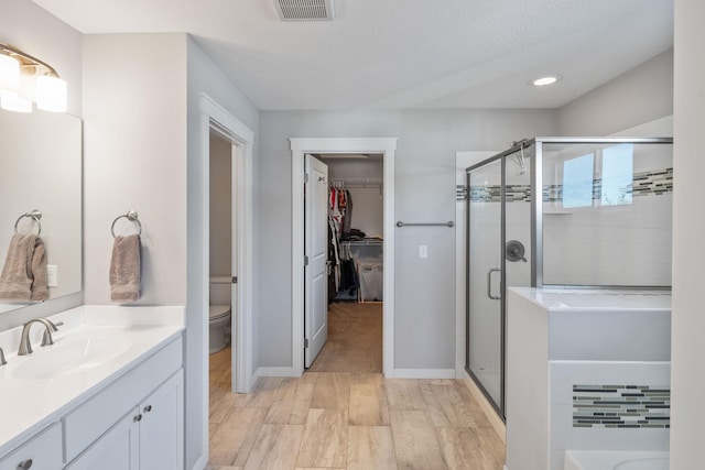 bathroom featuring visible vents, toilet, a stall shower, and vanity