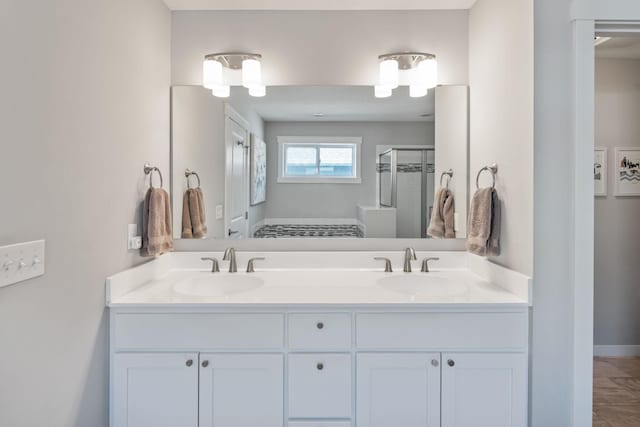 full bathroom featuring a shower stall, double vanity, baseboards, and a sink