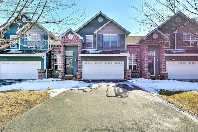 view of front of property with an attached garage, brick siding, and driveway