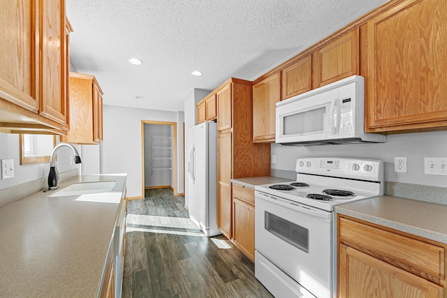 kitchen featuring a sink, a textured ceiling, dark wood-style floors, white appliances, and light countertops