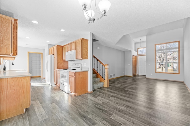 kitchen with white appliances, wood finished floors, visible vents, a sink, and light countertops