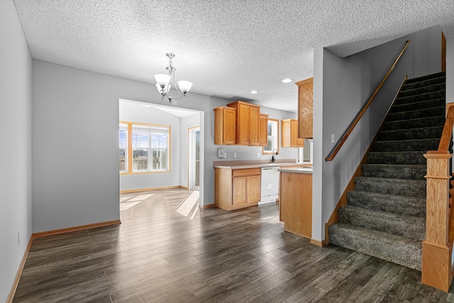 kitchen with a notable chandelier, dark wood-style flooring, light countertops, and white dishwasher