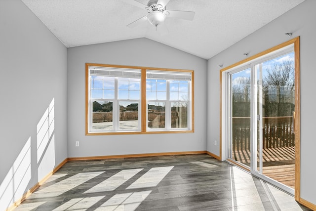 spare room with baseboards, a textured ceiling, wood finished floors, and vaulted ceiling