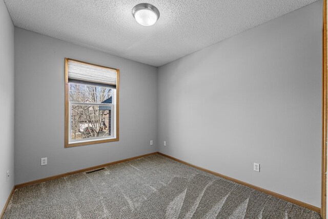 carpeted empty room featuring visible vents, a textured ceiling, and baseboards