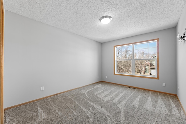 empty room with carpet flooring, visible vents, a textured ceiling, and baseboards