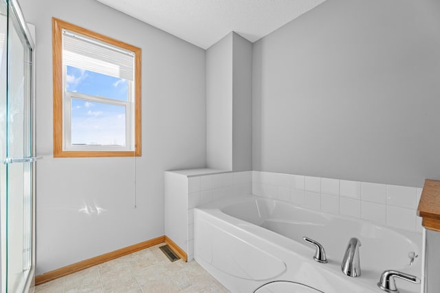 bathroom with tile patterned floors, a garden tub, baseboards, and a textured ceiling