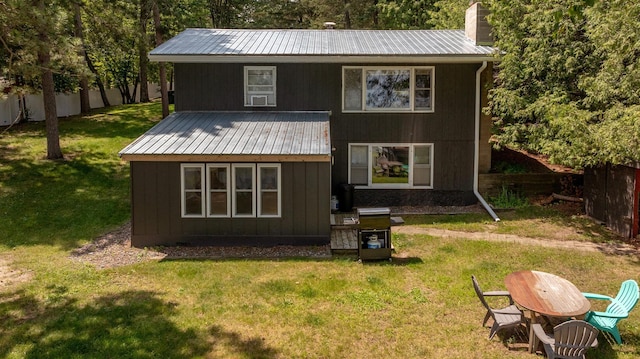 rear view of property with fence, a yard, a chimney, board and batten siding, and metal roof