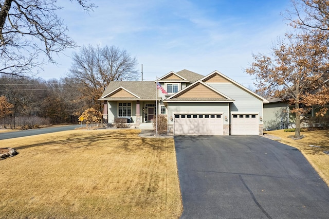 craftsman house with stone siding, driveway, a front yard, and a garage