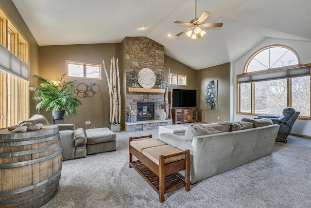 carpeted living area with high vaulted ceiling, a stone fireplace, and a ceiling fan